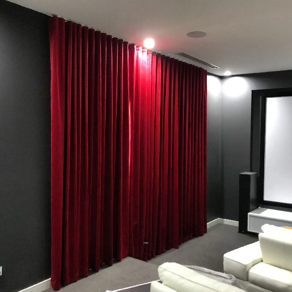 Rich red velvet curtains covering a wall in a living room, with a dark gray wall and white seating.