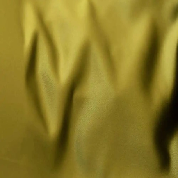 A close-up of shiny, green curtain fabric with soft folds.